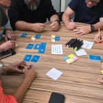 Equipe diversa participa de uma sessão de brainstorming com cartões e notas adesivas sobre uma mesa.