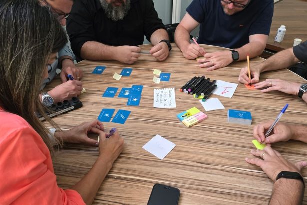 Equipe diversa participa de uma sessão de brainstorming com cartões e notas adesivas sobre uma mesa.