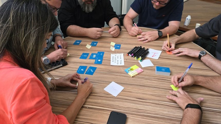Equipe diversa participa de uma sessão de brainstorming com cartões e notas adesivas sobre uma mesa.