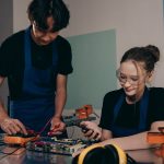 Dois jovens trabalham juntos em um projeto de eletrônica em um laboratório de formação técnica.