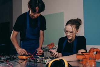 Dois jovens trabalham juntos em um projeto de eletrônica em um laboratório de formação técnica.
