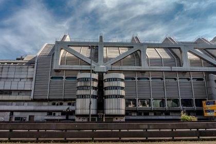 Fachada de um edifício institucional moderno, com estrutura metálica e grandes janelas.