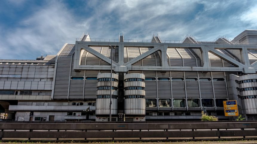Fachada de um edifício institucional moderno, com estrutura metálica e grandes janelas.